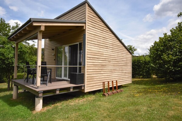 A modern wooden cabin with a covered deck, large windows, and a grassy yard. - Cottage in Germany With Sun Terrace & BBQ (Berlingen)