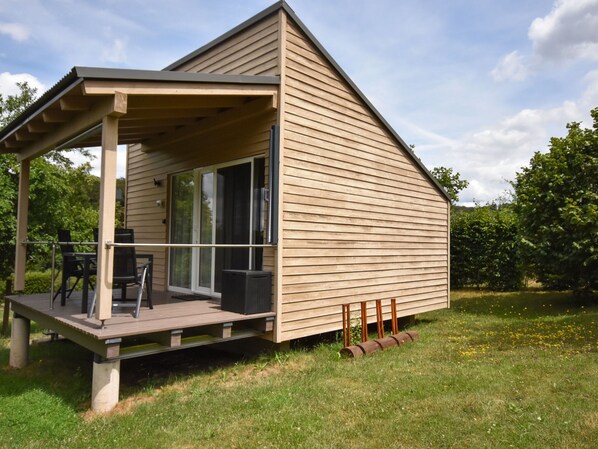 Una casa moderna de madera con un porche cubierto, grandes puertas correderas de vidrio y una pequeña terraza.