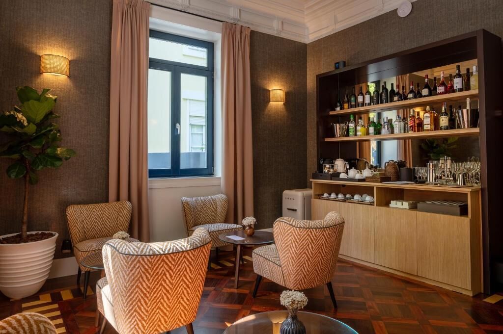 Vestíbulo de hotel con zona de bar, asientos y una planta grande en maceta.