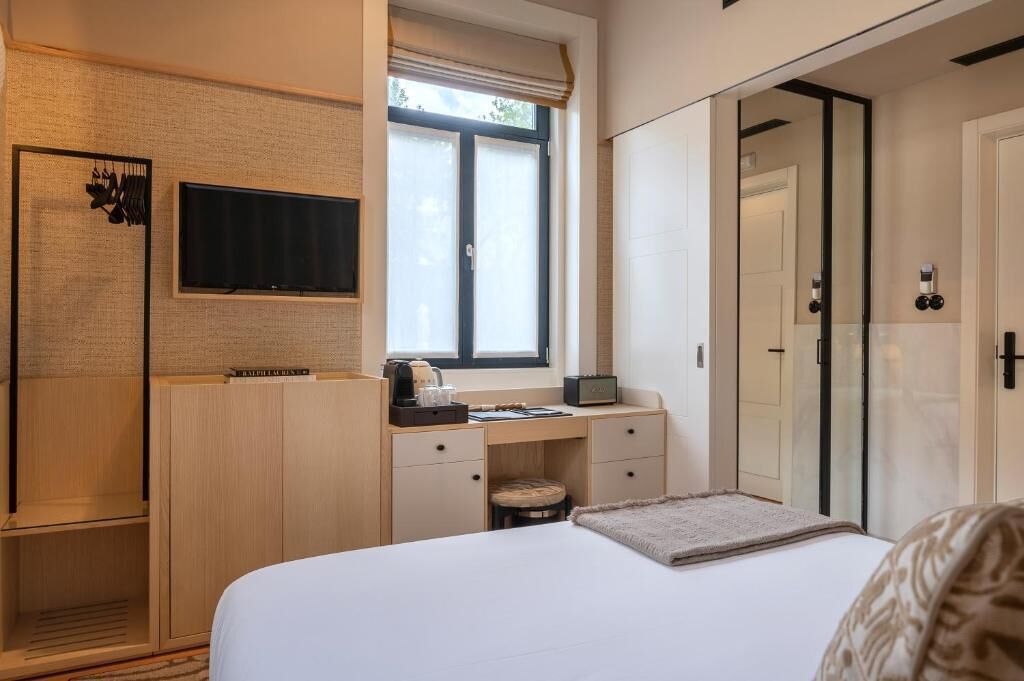 Een slaapkamer met een bed, een bureau, een televisie en een kledingkast.