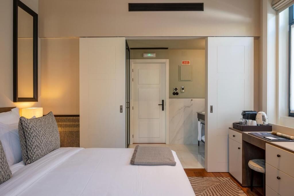 A hotel room with a bed, a desk, and a bathroom visible through an open door.