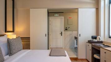 A hotel room with a bed, a desk, and a bathroom visible through an open door.