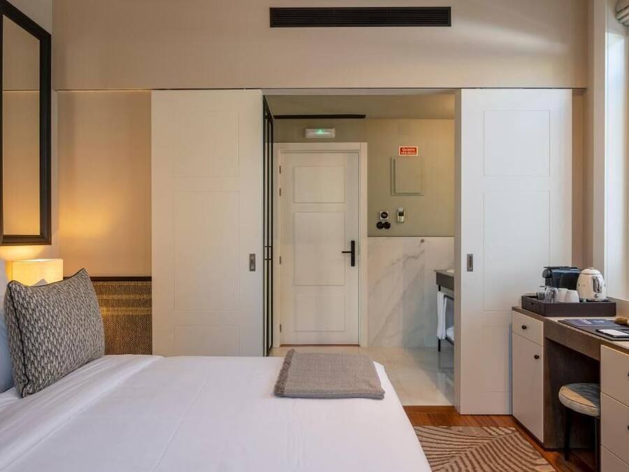 A hotel room with a bed, a desk, and a bathroom visible through an open door.