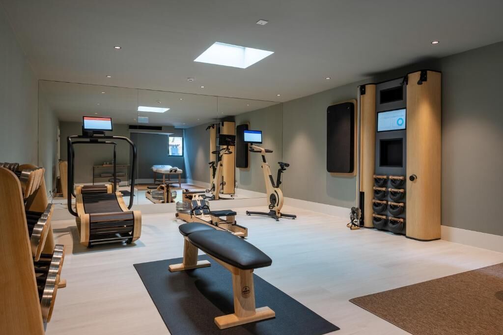 Un gimnasio moderno con diversos equipos de ejercicio, incluyendo cintas de correr, bicicletas estáticas y máquinas de pesas.