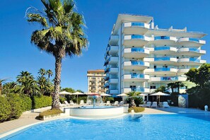 A hotel with a pool, palm trees, and a multi-story building with balconies. - Apartment in San Benedetto del Tronto Near Restaurants (San Benedetto del Tronto)