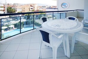 A balcony with a round table and chairs, overlooking a swimming pool and buildings. - Apartment in San Benedetto del Tronto Near Restaurants (San Benedetto del Tronto)