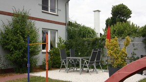A patio area with a table and chairs, a slide, and a climbing structure. - Ferienwohnung, Ribnitz-damgarten (Ribnitz-Damgarten)