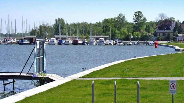 A marina with boats docked, a grassy area, and a no dogs sign. - Ferienwohnung, Ribnitz-damgarten (Ribnitz-Damgarten)