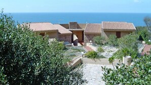 Ein Küsteneigentum mit Gebäuden mit Terrakotta-Dächern, einem Steinweg und Blick auf das Meer.