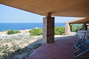 Eine Außenpatio mit steinernen Säulen, einem gefliesten Boden und Blick auf den Ozean.