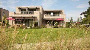 A modern two-story house with a well-maintained lawn and outdoor seating area. - Aalernhus Ferienhaus mit Hotel-spa St.peter-ording (St. Peter-Ording)