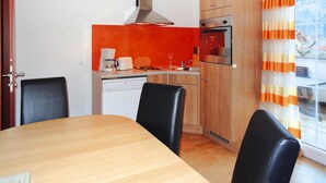 Une cuisine moderne avec une table et des chaises en bois, un four encastré et un lave-vaisselle.