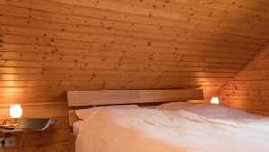 A wooden room with a bed, two bedside tables, and a lamp on each table. - Doppelhaushaelfte in Hasselfelde (Oberharz am Brocken)