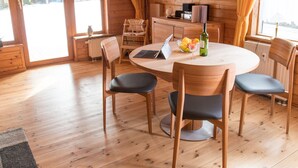 A wooden interior with a round dining table, four chairs, a laptop, a bottle of wine, and a television on the wall. - Doppelhaushaelfte in Hasselfelde (Oberharz am Brocken)