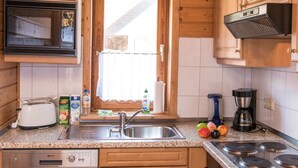 A kitchen with wooden cabinets, a stainless steel sink, a microwave, a toaster, and a coffee maker. - Doppelhaushaelfte in Hasselfelde (Oberharz am Brocken)