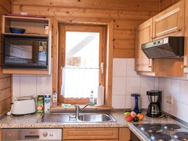 A kitchen with wooden cabinets, a stainless steel sink, a microwave, a toaster, and a coffee maker.