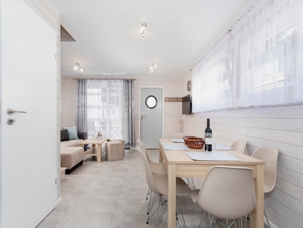 Une pièce moderne et bien éclairée, comprenant une table à manger, des chaises, un canapé et un petit coin cuisine.