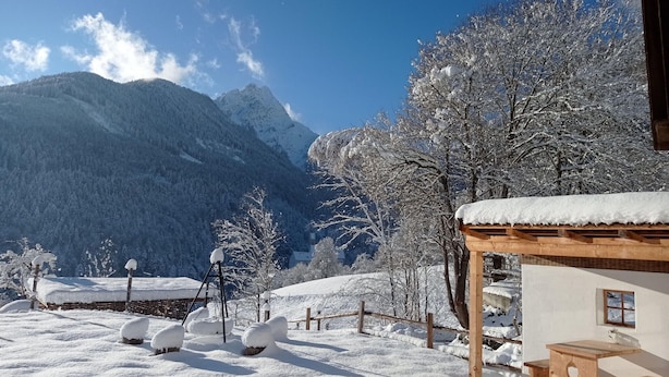 A snow-covered outdoor area with a wooden structure, possibly a patio or seating area, and a mountain backdrop. - Rossweid hut With a Fantastic View (Stans)