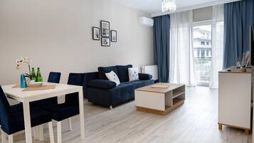 Una sala moderna con comedor, sofá, mesa de centro y vistas al exterior.