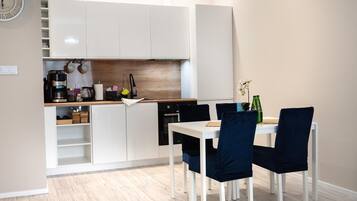 A compact kitchen with white cabinets, a coffee machine, and a dining area with a table and chairs.