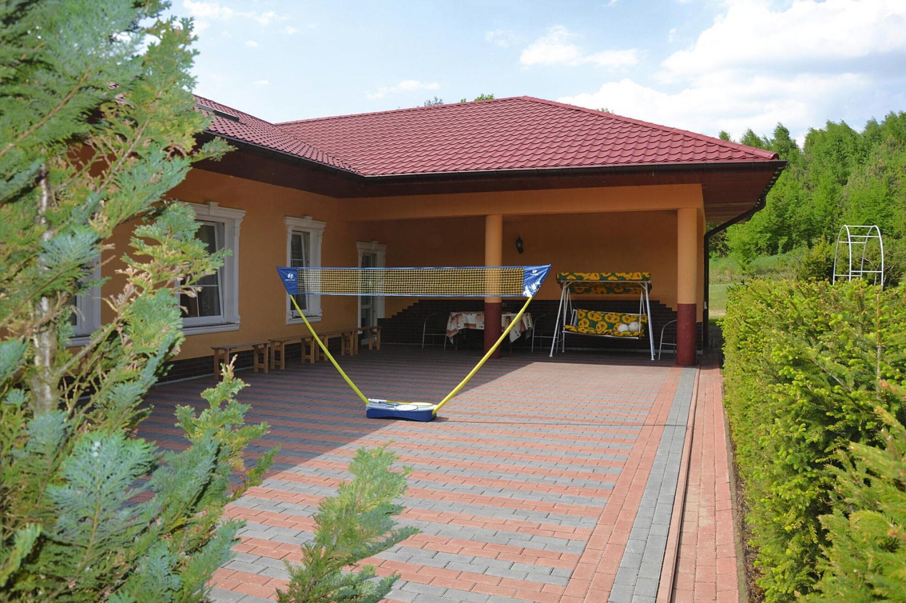 A building with a red-tiled roof, a covered patio area, and a badminton net set up.
