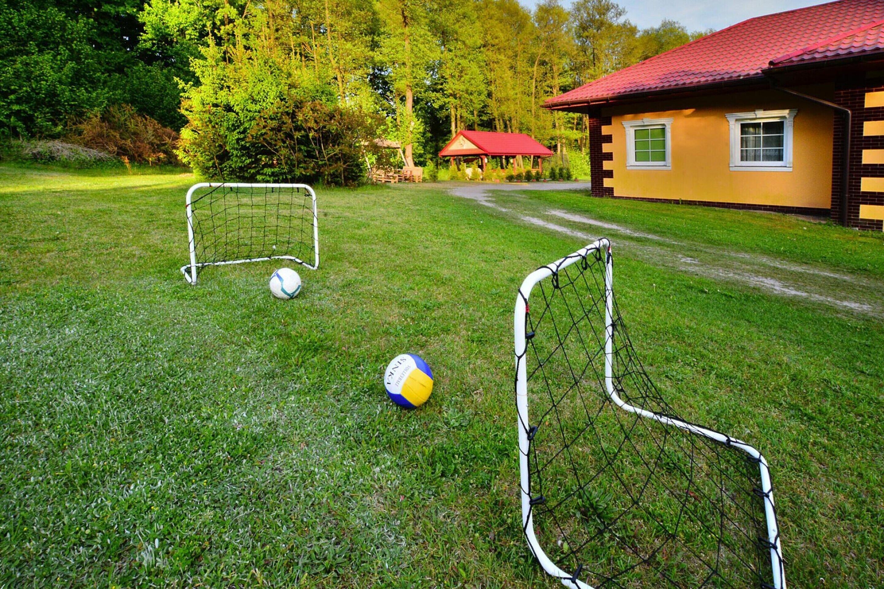 A grassy field with two soccer goals and a ball.