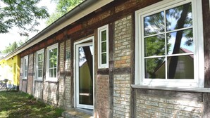 Un bâtiment en briques doté de nombreuses fenêtres et d’une porte, entouré d’une zone herbeuse.