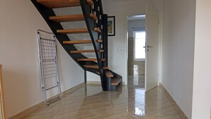 Un intérieur moderne avec un escalier en bois, une étagère en métal et un sol carrelé.