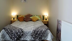 A neatly made bed with patterned bedding, two wall-mounted lamps, and two framed artworks above it. - Seaside Apartment in Dziwnow Baltic (Dziwnów)