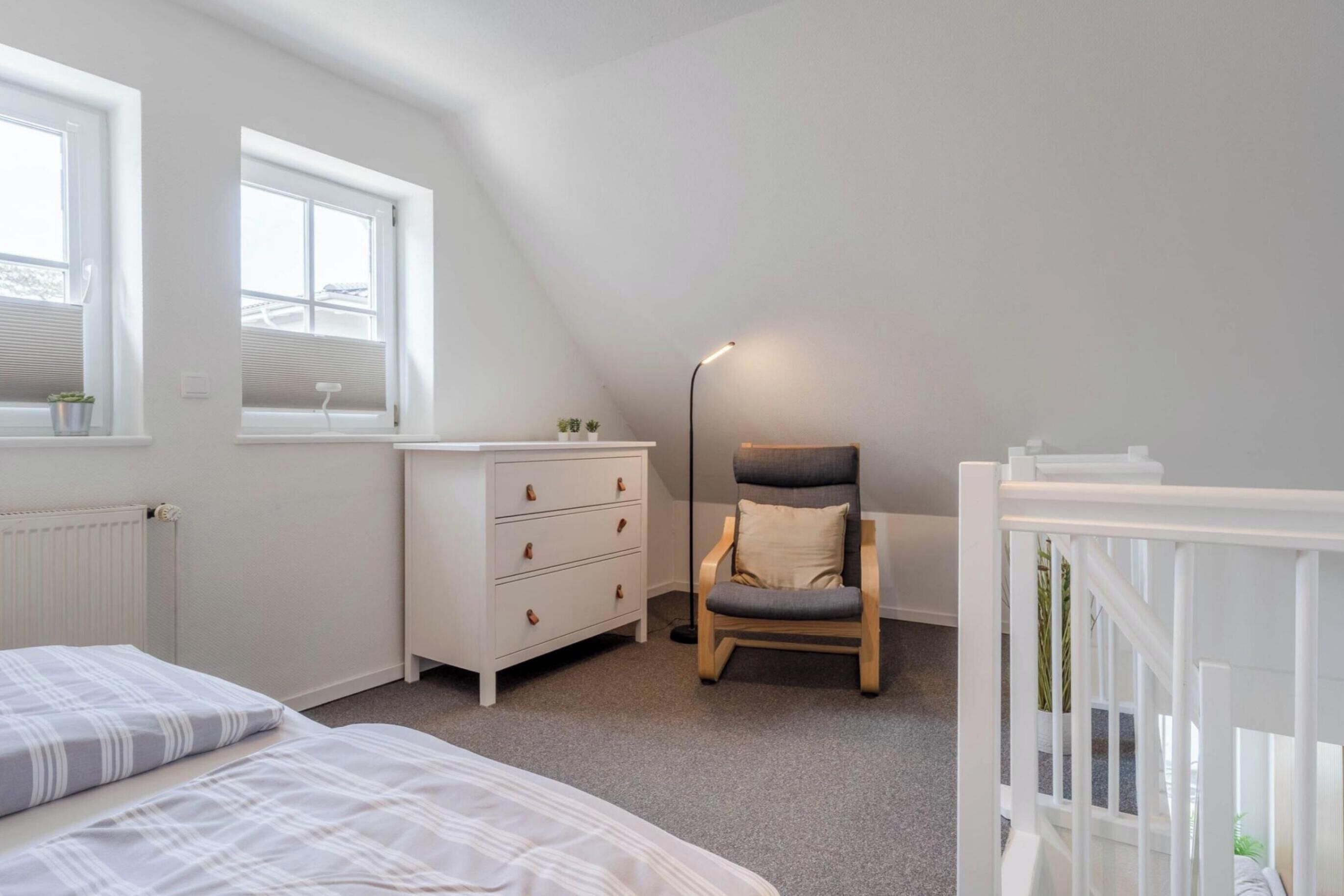 A bedroom with a bed, dresser, chair, and crib.