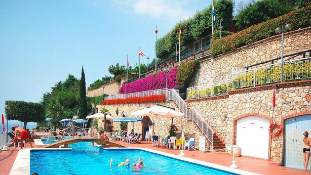 A swimming pool area with a stone wall, a staircase, and a lifebuoy. - Holiday Flat in Pretty Residence With Communal Pool in Pietra Ligure (Pietra Ligure)
