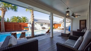Un espacio al aire libre techado con piscina, sillas de descanso y valla de madera.
