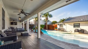 Un espacio exterior cubierto con piscina, asientos y ventiladores de techo.