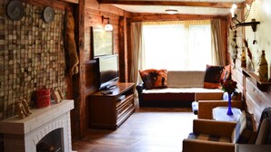 A cozy living room with a fireplace, wooden walls, a television, and comfortable seating. - Cozy Holiday Home, Junoszyno (Stegna)