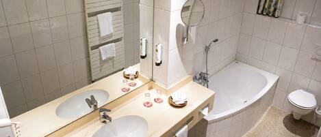 A bathroom with two sinks, a bathtub, a toilet, and a mirror.