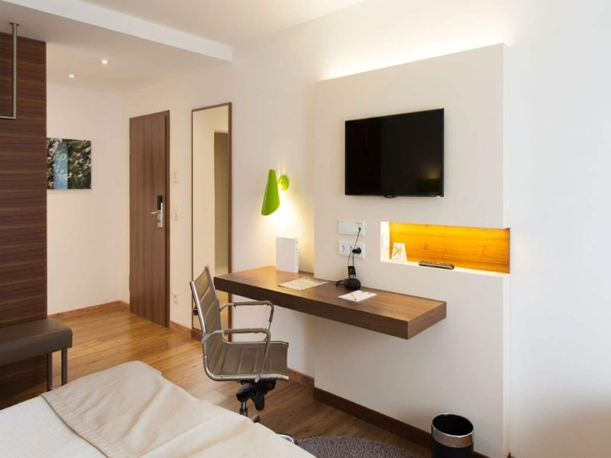 Une chambre d’hôtel comprenant un lit, un bureau avec une chaise, une télévision et un miroir.