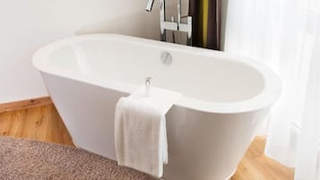 Ein modernes Badezimmer mit freistehender Badewanne, einem Handtuch und Holzboden.