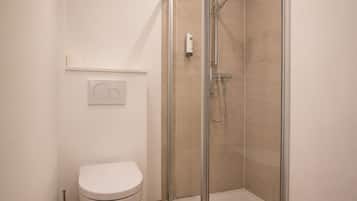 Ein modernes Badezimmer mit Toilette, einer Dusche mit Glastür und Bedienfeld an der Wand.