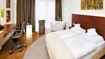Habitación de hotel con cama, escritorio, silla, bañera y ventana con cortinas.