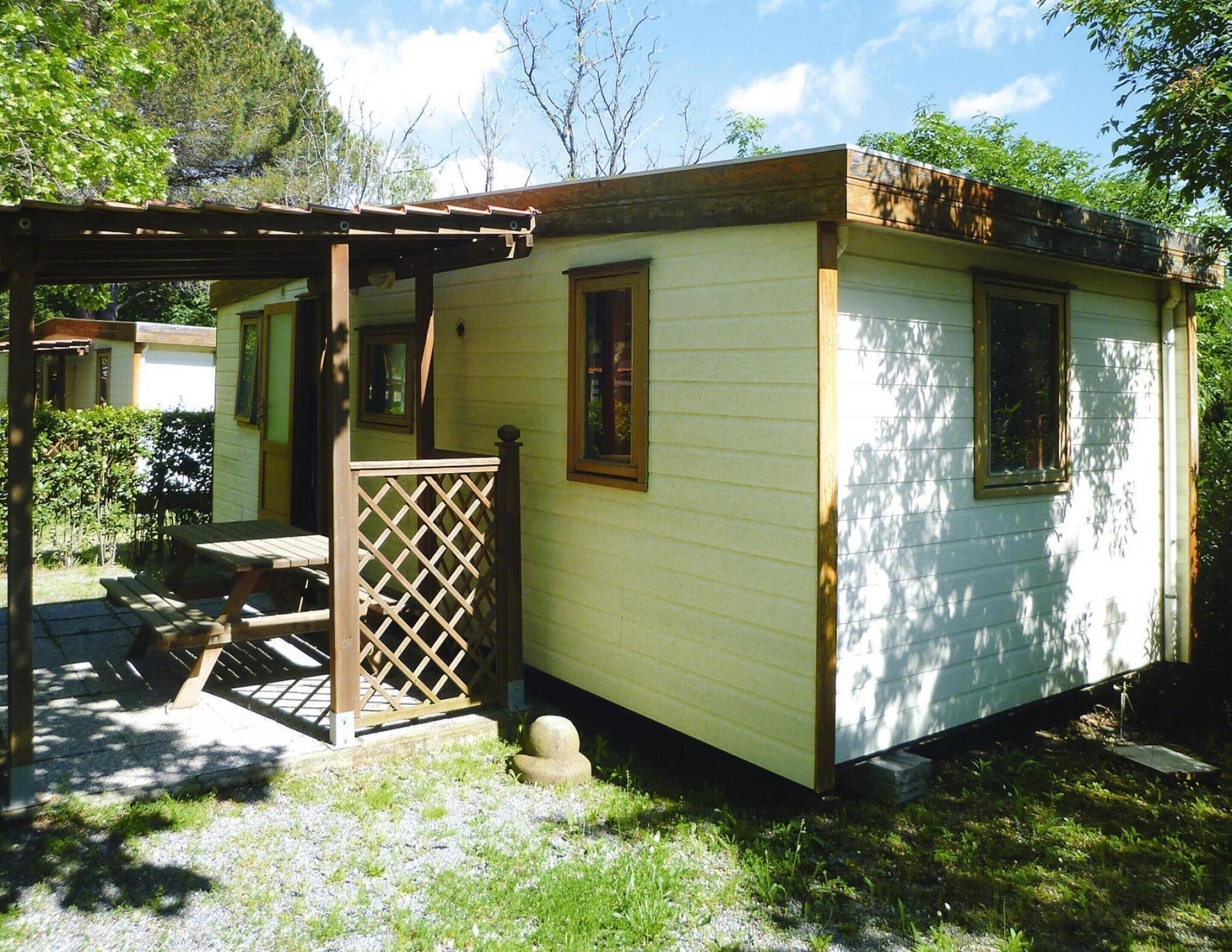 A small, single-story cabin with a covered porch and a fenced patio area.