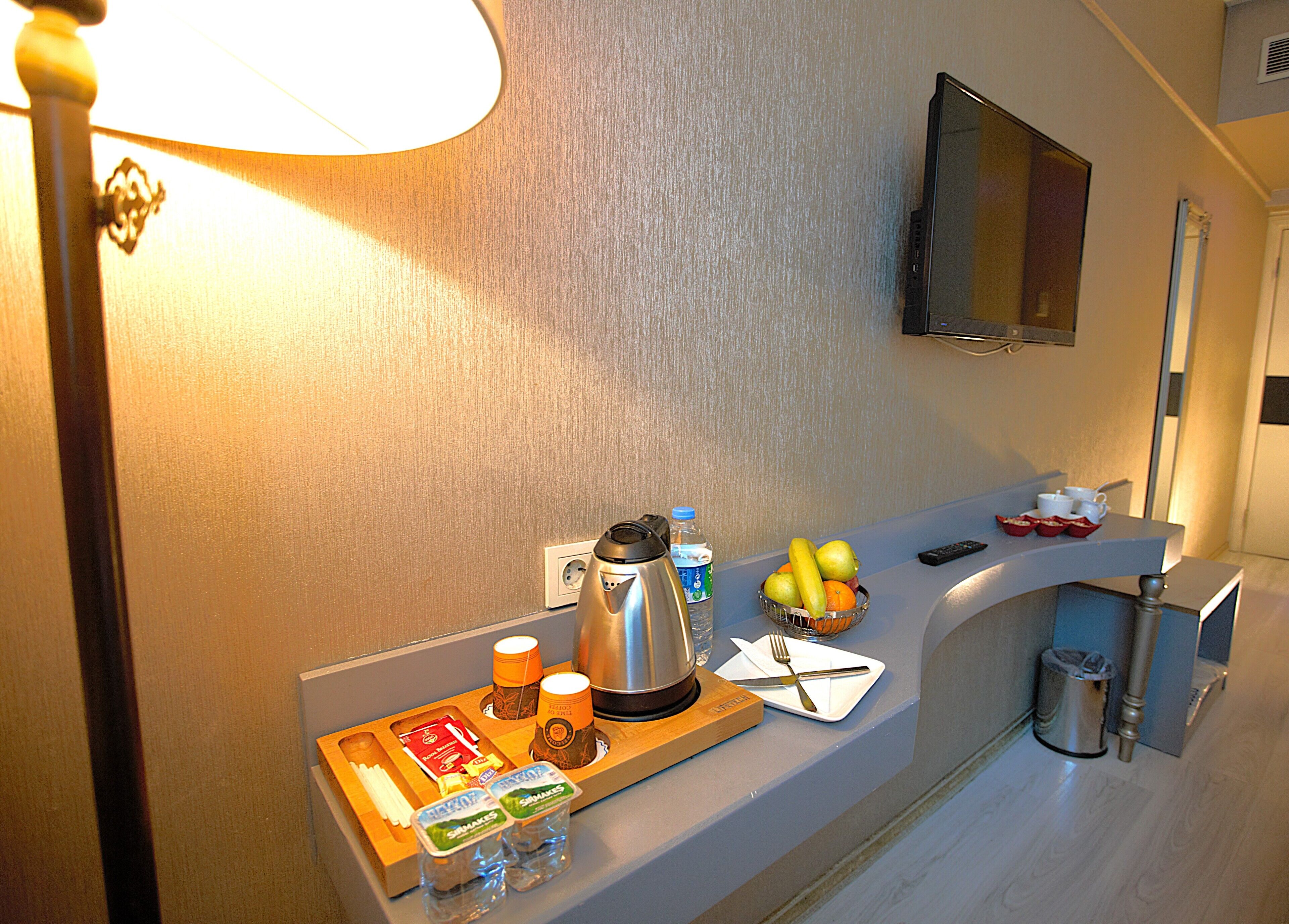 A hotel kitchenette with a coffee maker, fruit bowl, and condiments on the counter.