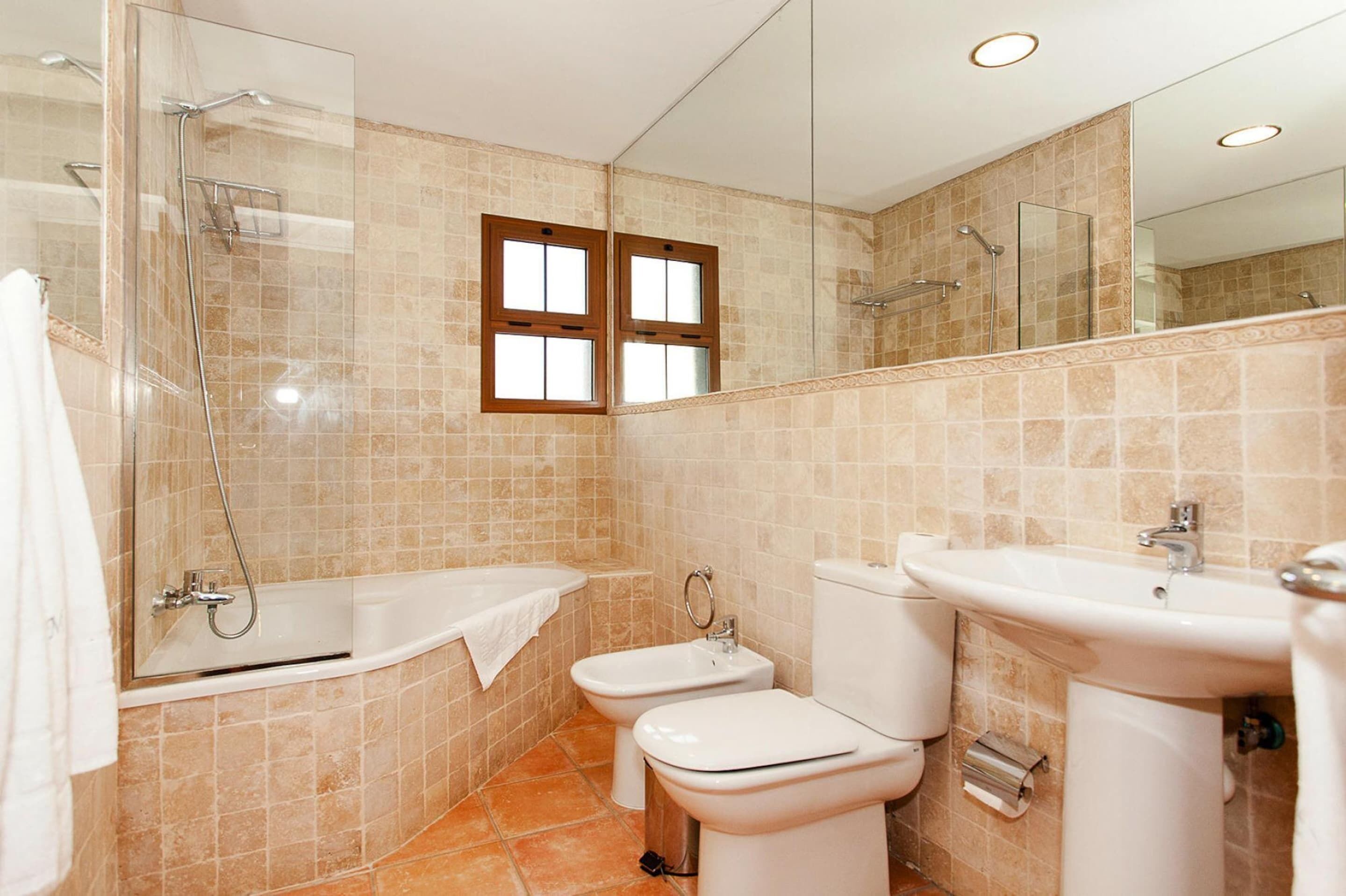 Une salle de bain moderne dotée d’une douche à parois de verre, d’une baignoire, d’un bidet, de toilettes et d’un lavabo.