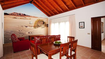 Un comedor con una mesa y sillas de madera, un sofá rojo y un mural de un desierto en la pared.