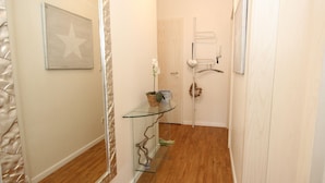 A hallway with a glass shelf holding a potted plant and a decorative item. - Strandnahe Ferienwohnung in Duhnen (Cuxhaven)