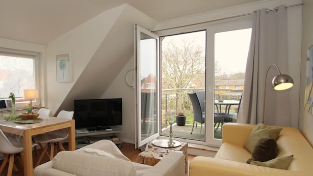 A modern living room with a TV, a dining table, and a sofa. - Strandnahe Ferienwohnung in Duhnen (Cuxhaven)