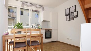 A compact kitchen with a dining table and chairs, a built-in oven, and a view of the balcony through the window. - Reihenhaus in Malchow (Malchow)