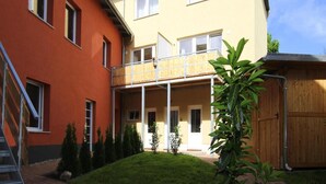A two-story building with a balcony and a small garden area. - Reihenhaus in Malchow (Malchow)