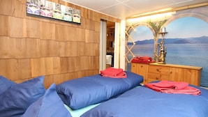 Una stanza con due letti, pareti in legno, un comò in legno e vista sul mare.