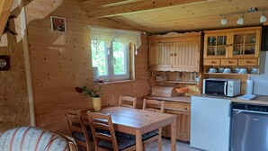 A cozy cabin-style kitchen with wooden cabinets, a dining table, and chairs. - Cottage in Koscierzyna With Lake Nearby (Koscierzyna)