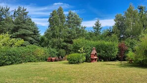 A grassy outdoor area with a red structure, surrounded by dense trees and shrubs. - Cottage in Koscierzyna With Lake Nearby (Koscierzyna)